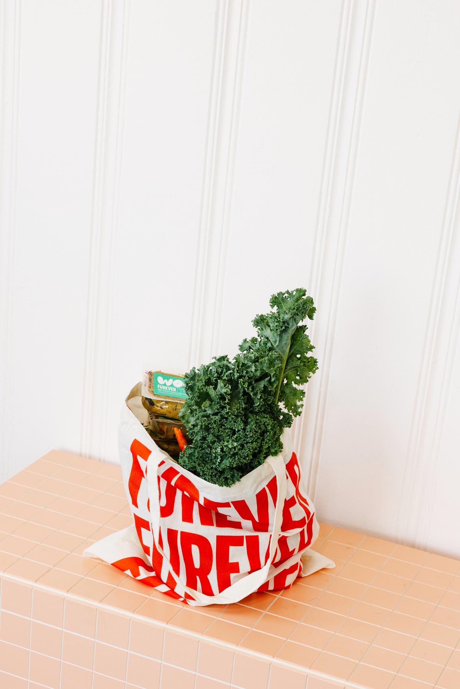Kale in a reusable produce bag on a wooden surface with a white background