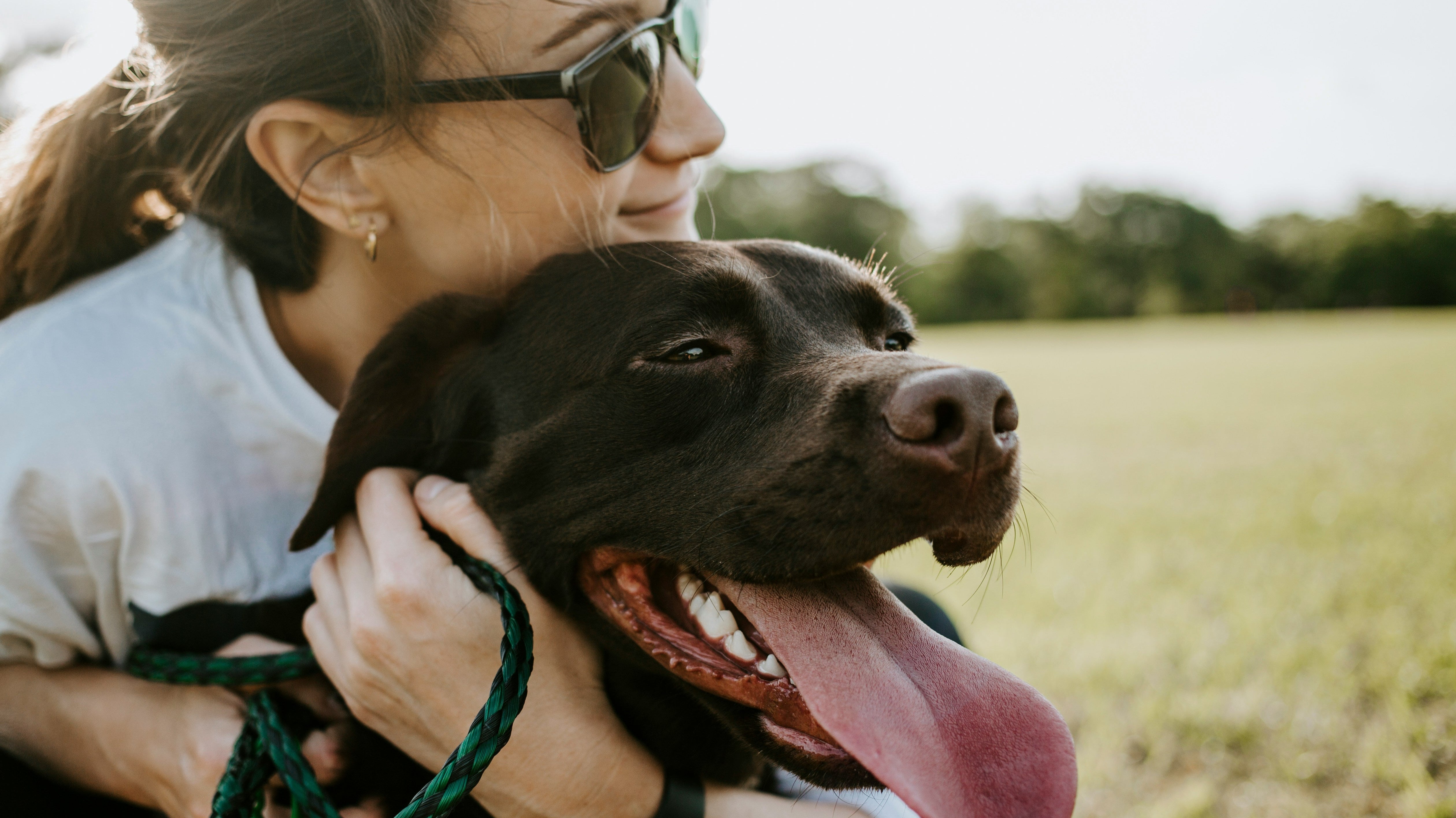 Woman hugging a black dog in an outdoor setting