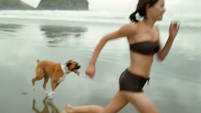Woman running with a dog on a beach