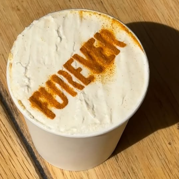 Cappuccino with 'Brewer' logo on a wooden surface